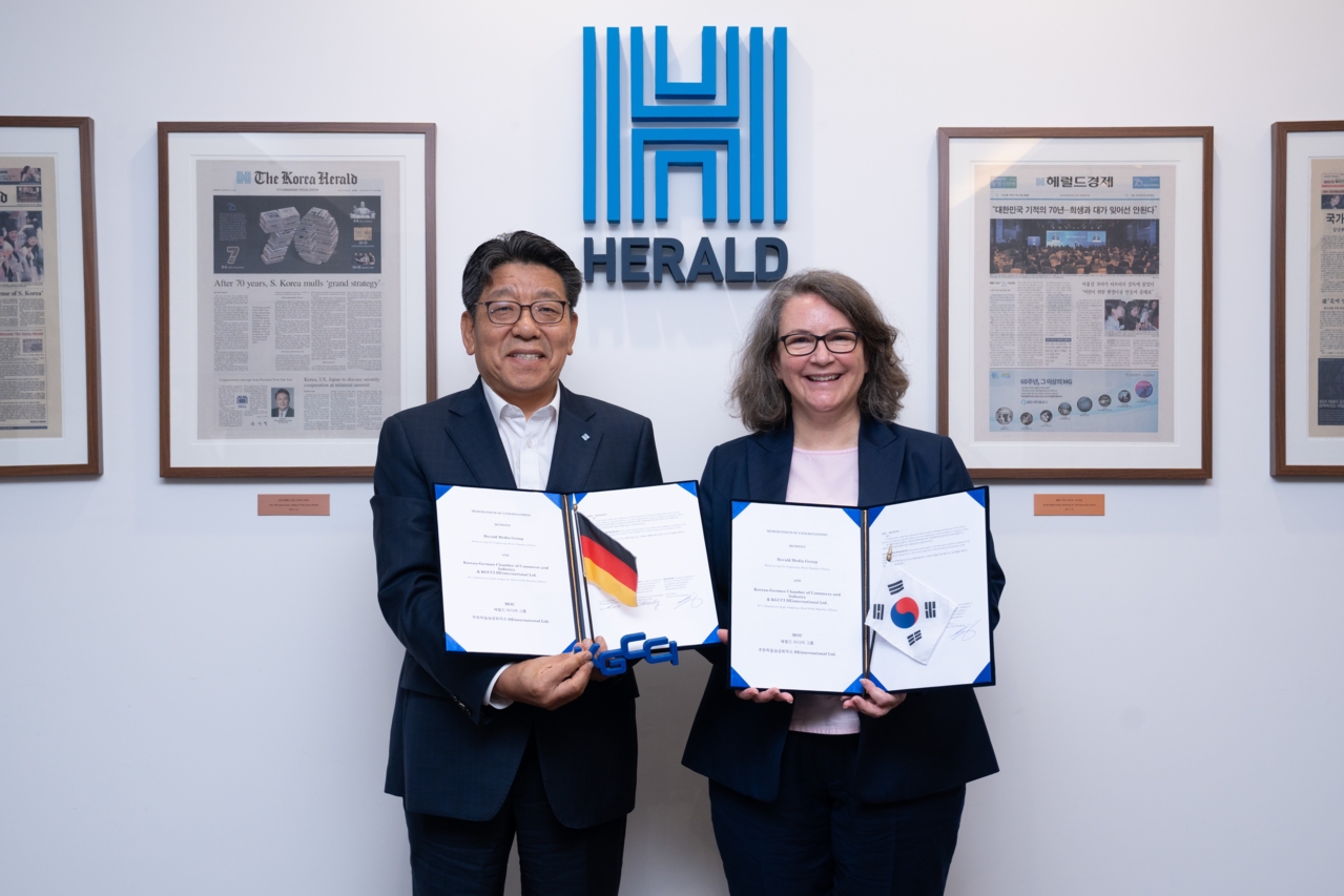 The signed media partnership agreement held open between the Herald Media Group publisher and the KGCCI President and CEO, with the German and Korean flags between them